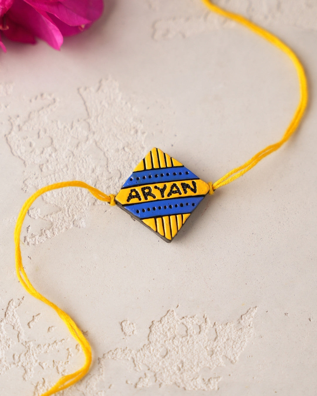 Yellow and blue rakhi with name on a light background